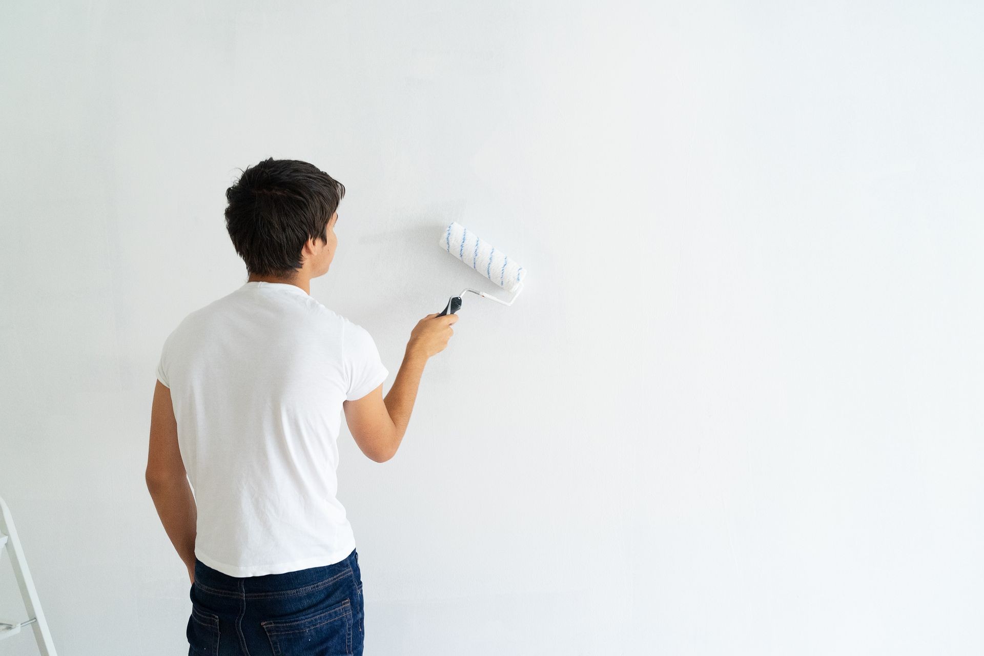 Young men painting wall of the house, do it yourself home renovation concept